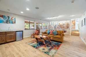 A spacious living area with a wooden coffee table, a brown leather sofa, and a colorful rug.