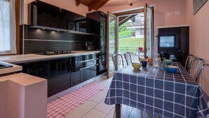 A modern kitchen with black cabinets, a stainless steel countertop, and a dining area with a checkered tablecloth.