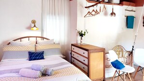 Un dormitorio con cama, cómoda, silla y perchero.