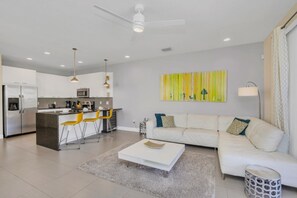 Um espaço de estar moderno com cozinha, um sofá branco e uma mesa de centro.
