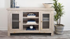 Un mueble bajo de madera para televisor con un televisor montado encima, un florero con una planta, un cuenco y una planta en maceta al lado.