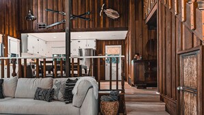 Un vaste espace de vie doté d  ’un plancher en bois, d’un canapé gris agrémenté de coussins à motifs, et d’un coin repas avec des chaises en bois et une table blanche.