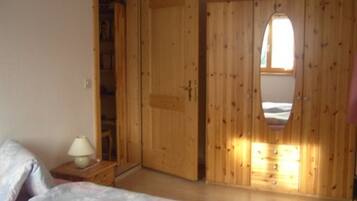 Ein Schlafzimmer mit einem Bett, einem Nachttisch, einem Holzschrank und einem Fenster.