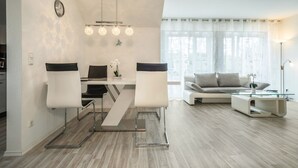 Ett modernt vardagsrum med en matplats, en soffa, ett soffbord och en lampa.
