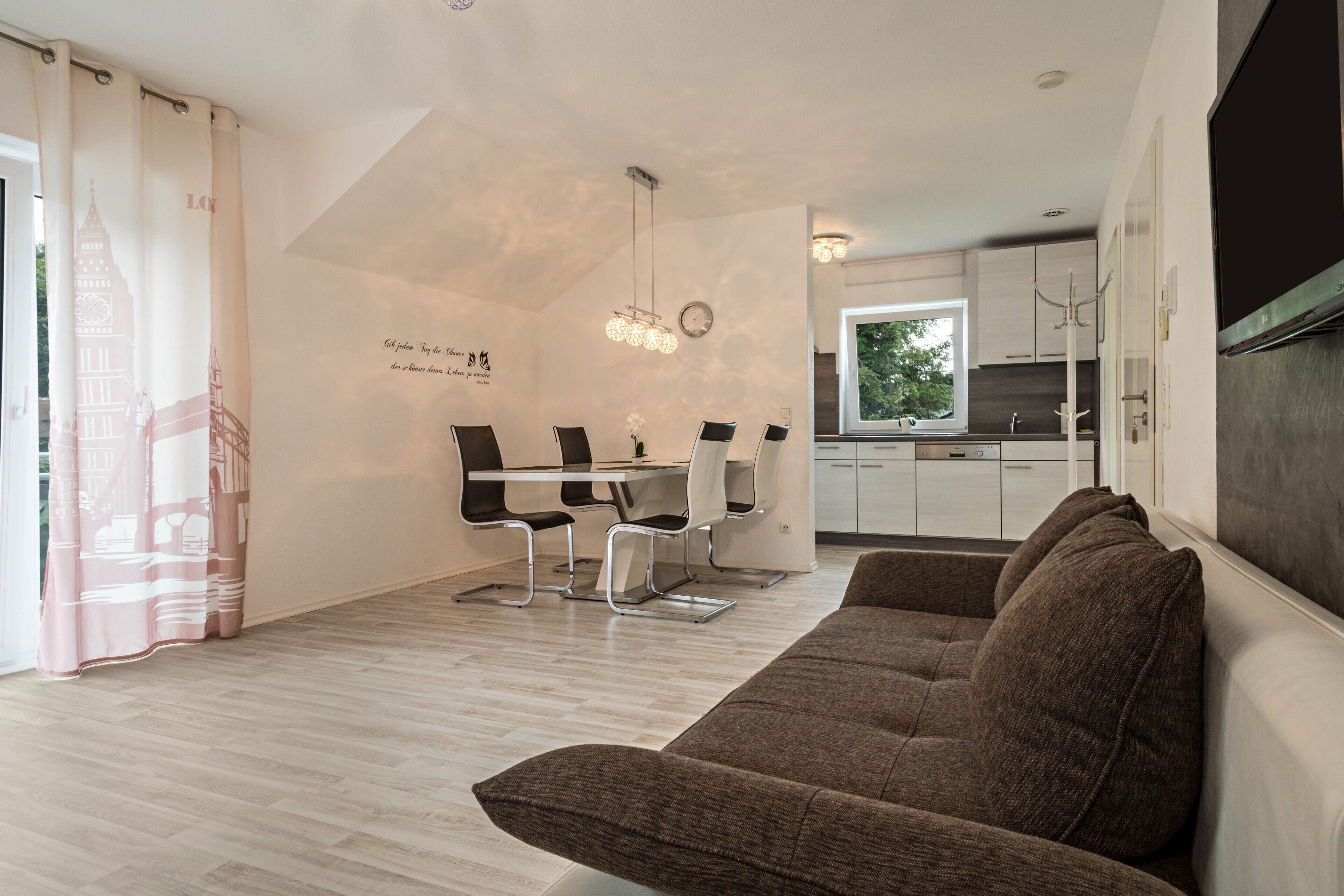 Ein modernes Interieur mit Essbereich, Küche und einem großen Fenster.