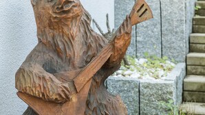 Une sculpture en bois représentant un ours tenant un instrument de musique.