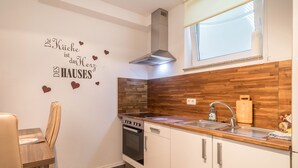 Una cocina moderna con un protector contra salpicaduras de madera, una campana de acero inoxidable, un horno empotrado y un ventanal sobre el fregadero.