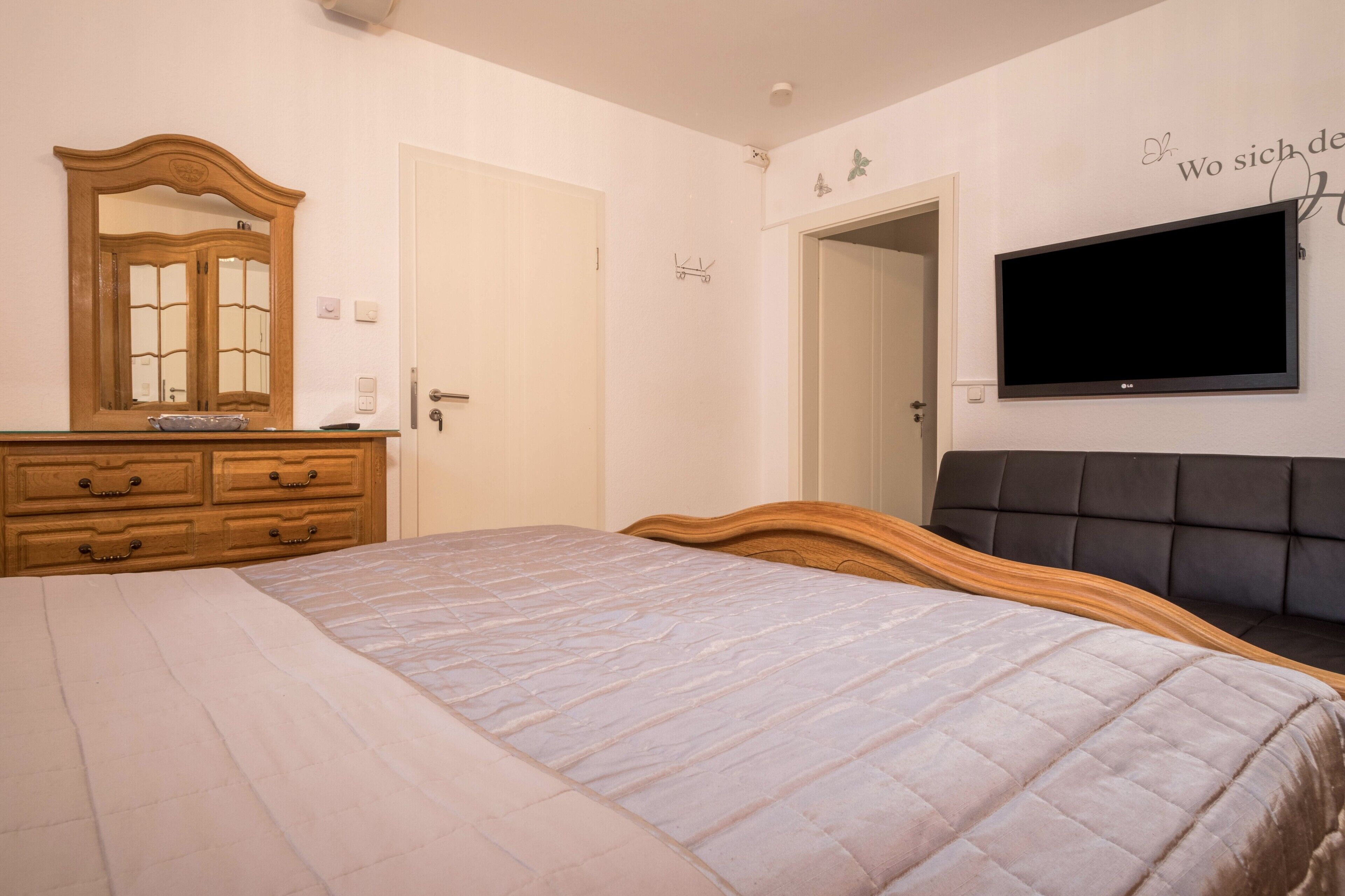 Una camera da letto con un letto, una cassettiera, un televisore e una porta.