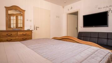 Una camera da letto con un letto, una cassettiera, un televisore e una porta.