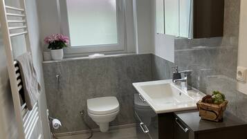 A modern bathroom with a toilet, sink, and shower.
