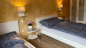 A modern bedroom with a bed, bedside tables, a small desk, and a wall-mounted lamp.