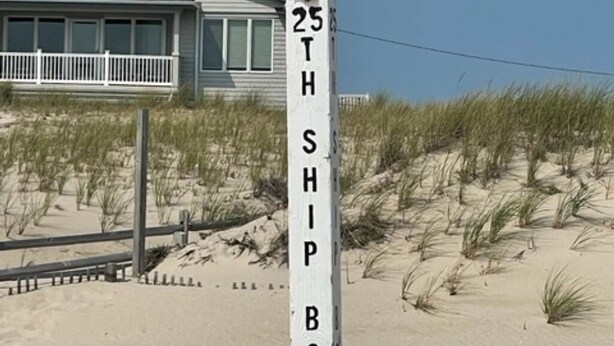 A beach sign with the text "25TH SHIP BOTTOM" and a seagull perched on top.