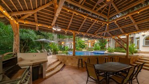 An outdoor patio area with a grill, seating, and a swimming pool.