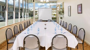 Ein Konferenzraum mit einem langen Tisch, Stühlen, einer Kandelaber und großen Fenstern.
