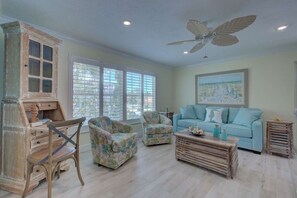 A spacious living room with a light blue sofa, two armchairs, a wooden coffee table, and a ceiling fan. - Lulu's Key House | Sleeps 20 | Walk to Beach (Siesta Key)