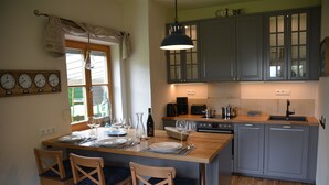 Una cocina con armarios de madera, una mesa de comedor para cuatro personas y un reloj en la pared.