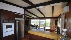 A kitchen with a wooden island, built-in oven, and refrigerator. There is a coffee maker and a toaster on the counter. - Sylvan waters Mallacoota (Mallacoota)