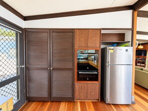 A compact kitchen with a built-in oven, a stainless steel refrigerator, and wooden cabinetry. - Sylvin Waters, Mallacoota (Mallacoota)