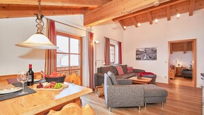 Een ruime woonkamer met een houten eettafel, een bank en een open haard.