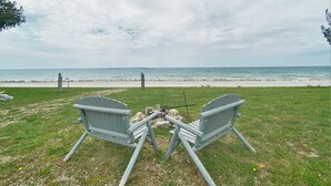 Zwei Adirondack-Stühle, die auf einen Strand mit Blick auf den Ozean zeigen.