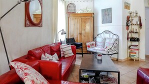 Ein Wohnzimmer mit einem roten Sofa, einem Metallstuhl, einem Couchtisch und einem Bücherregal.