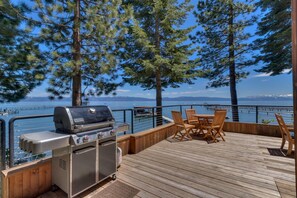 Terraza con una parrilla y asientos al aire libre con vista a un lago.