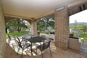 Eine Terrasse im Freien mit Säule aus Ziegeln, einem Tisch und Stühlen.