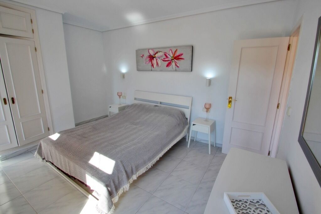 Une chambre à coucher comprenant un lit, des tables de chevet, une commode, une porte et une œuvre d’art accrochée au mur.
