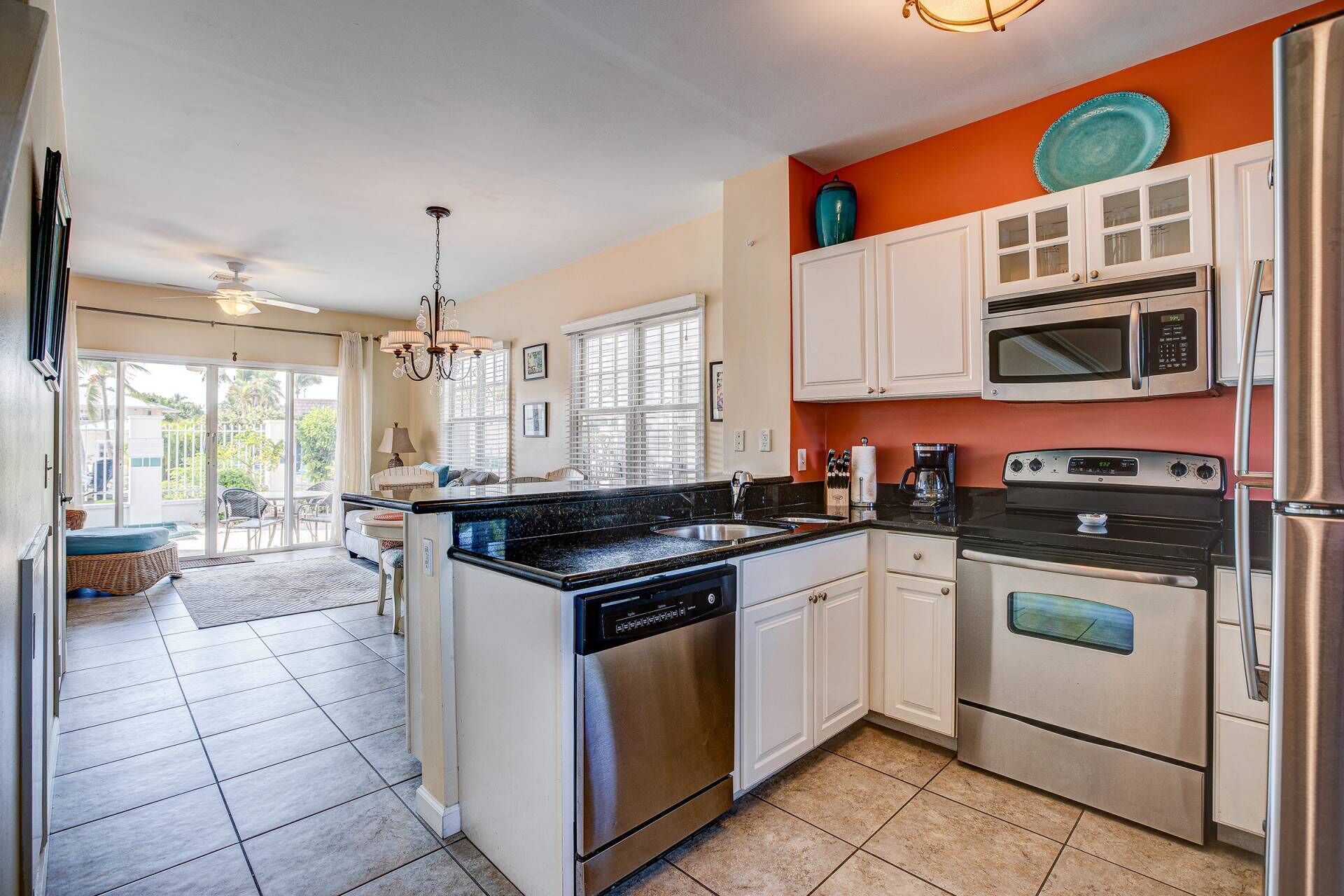 A kitchen with white cabinets, a black countertop, a dishwasher, a microwave, and a stove.