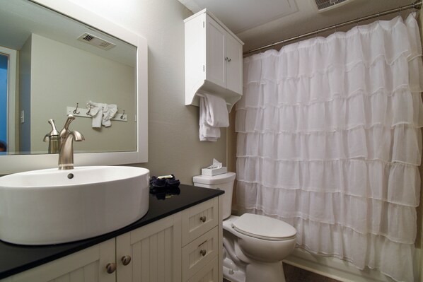 A bathroom with a white sink, toilet, and shower curtain.