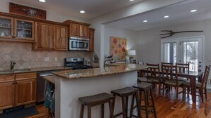 A kitchen with wooden cabinets, a granite countertop, a built-in microwave, and a dining area with wooden chairs and a table.
