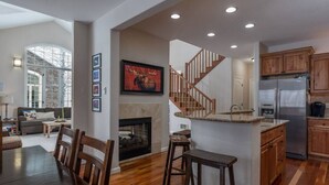 A spacious kitchen with wooden cabinets, a stainless steel refrigerator, and a built-in island with stools.