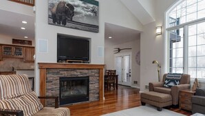 A spacious living room with a fireplace, comfortable seating, and a large window.
