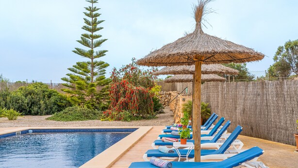 A swimming pool with lounge chairs and a thatched umbrella. - Sa Punta Ses Salines Holiday Home with Pool and Wi-Fi (Ses Salines)