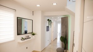 A modern hallway with a mirror, potted plants, a stone bench, and a door leading to another room. - Spacious Sea View Penthouse with Sea View, Wi-Fi & Terrace (Torremolinos)