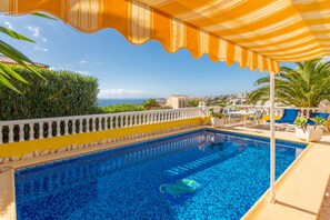 A swimming pool with a view of the sea, a white balustrade, and a yellow and white striped awning. - Villa Casa dos Leones with sea view, pool, air conditioning, Wi-Fi, garden & terrace (Benitachell)