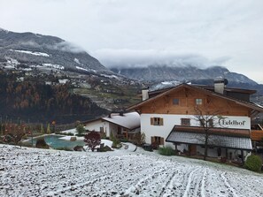 Una cabaña con piscina, rodeada de campos nevados y montañas.