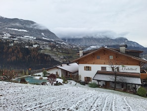 Un chalet doté d’une piscine, entouré de champs et de montagnes enneigés.
