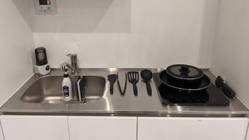 A compact kitchen with a stainless steel sink, a built-in stove, and various utensils.