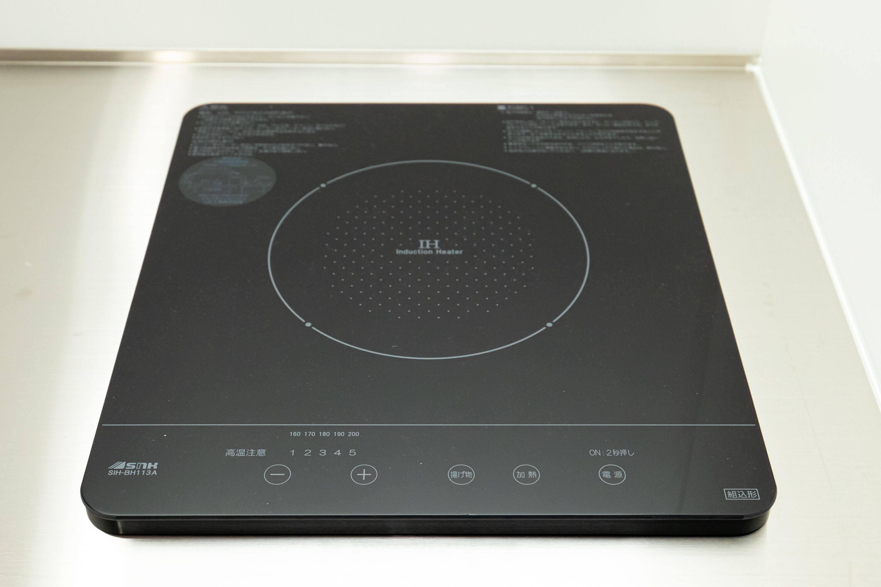 A black induction heater with a circular heating element, control buttons, and a brand logo.