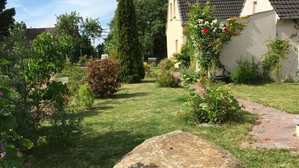 A garden with a large rock, a pathway, and a building with a tiled roof. - House - Vacation rental in Bartelshagen II (Bartelshagen II bei Barth)