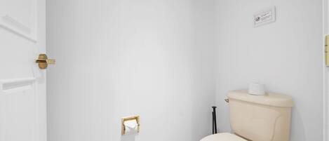 Un baño pequeño y limpio, con inodoro, dispensador de toallas y porta papel higiénico en la pared.