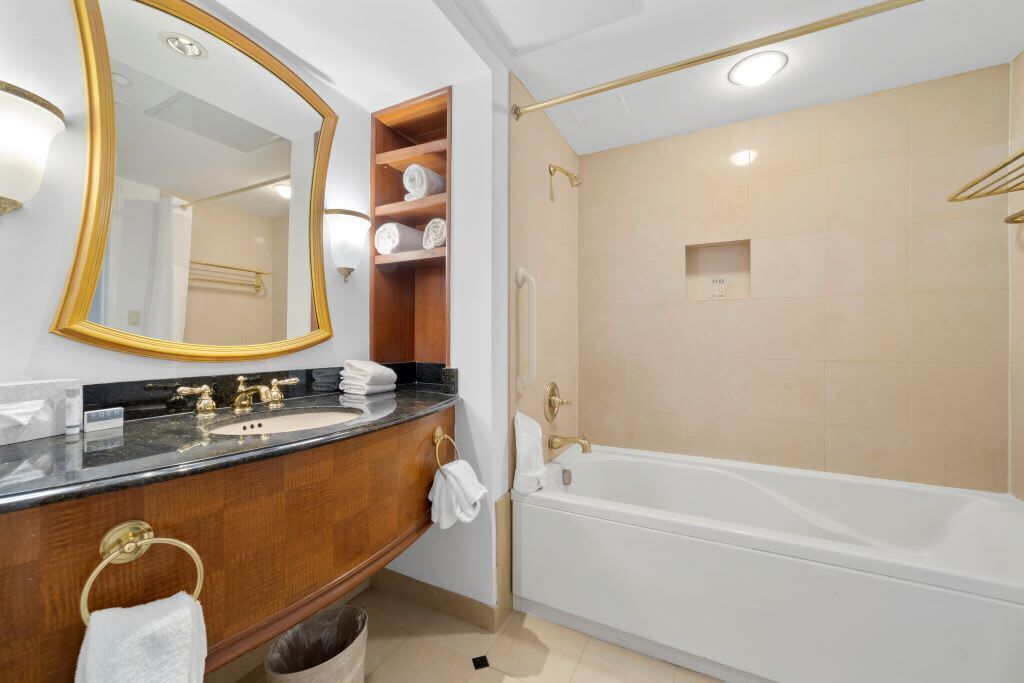 A modern bathroom with a large mirror, a vanity with a sink, and a separate shower area.