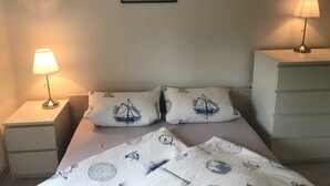 Un dormitorio con una cama, dos mesitas de noche, dos lámparas, un aparador y un cómoda.