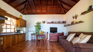 Una cucina con mobili in legno, un tavolo da pranzo con sedie, una televisione e un divano.