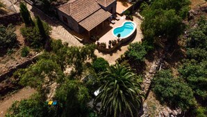 Una vista aerea di una casa con piscina, immersa nel verde e circondata da un muro in pietra.