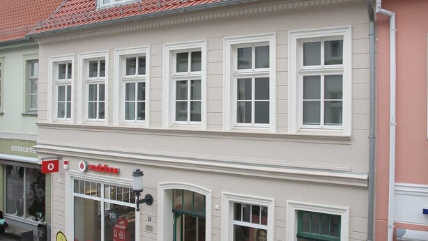 Un bâtiment doté de nombreuses fenêtres et d’un toit recouvert de tuiles rouges.