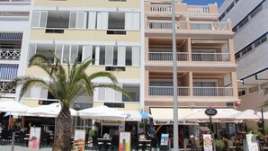 A multi-story building with balconies, outdoor seating, and palm trees. - Miramar Atico, Spain (Puerto Naos)