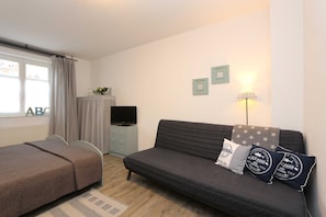 Quarto com cama, sofá, televisão e abajur.