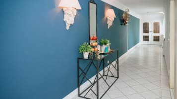 Un corridoio con una parete blu, un tavolo consolle nero con oggetti decorativi e una porta bianca in fondo.
